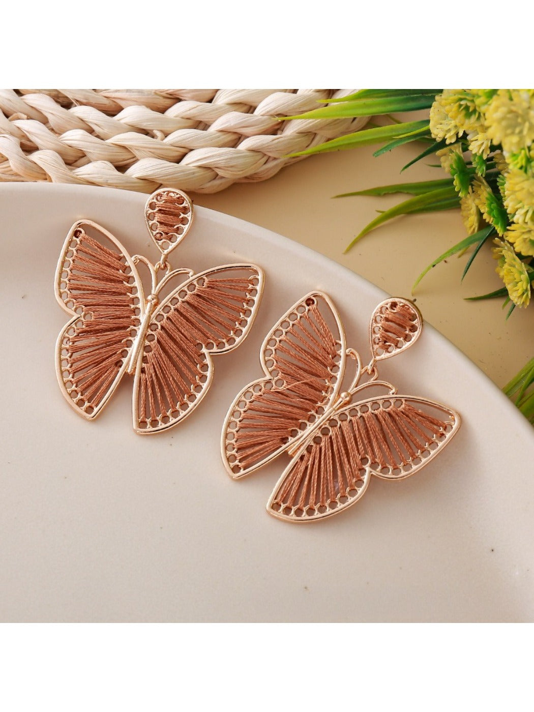 Butterfly drop earrings hanging from a jewelry stand with natural lighting