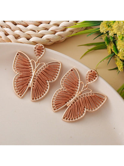 Butterfly drop earrings hanging from a jewelry stand with natural lighting