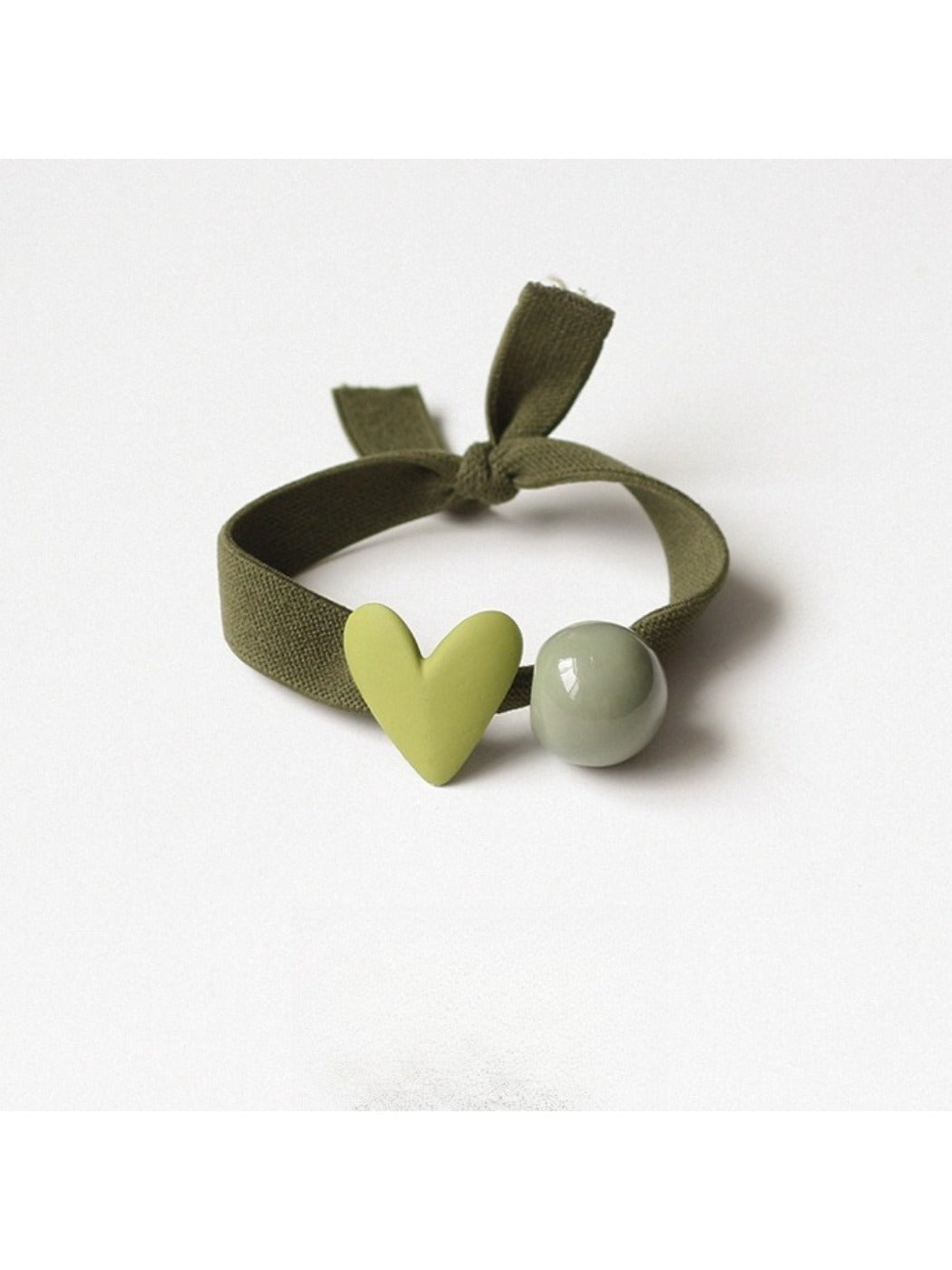 Multiple heart-decorated hair ties arranged in a circle on a pastel background