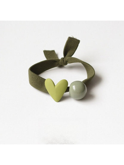 Multiple heart-decorated hair ties arranged in a circle on a pastel background