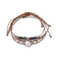 Lovra bracelet with beads and woven cord laid out on white background