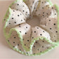 Pink ruffled scrunchie with white polka dots styled in a ponytail