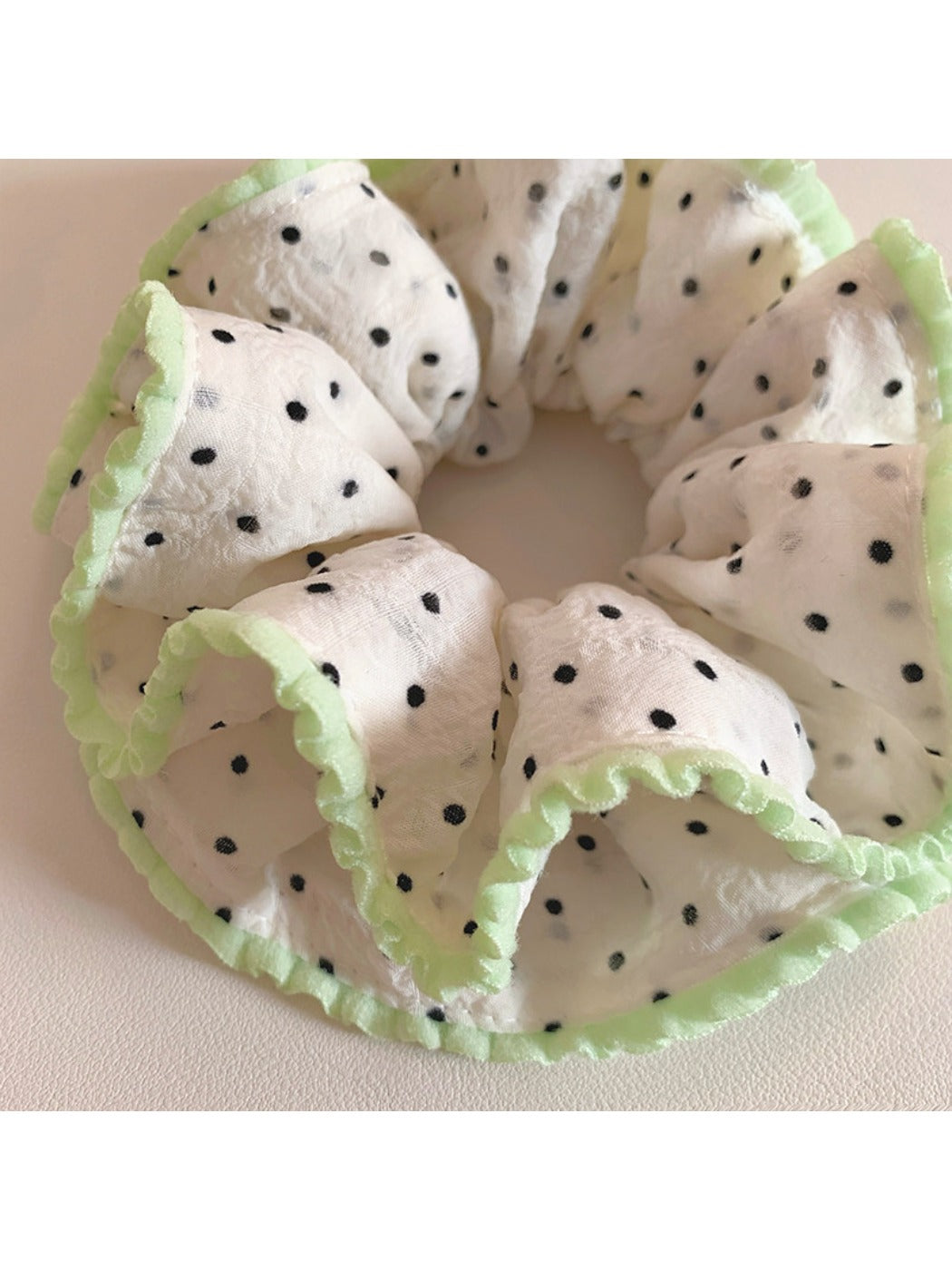 Pink ruffled scrunchie with white polka dots styled in a ponytail