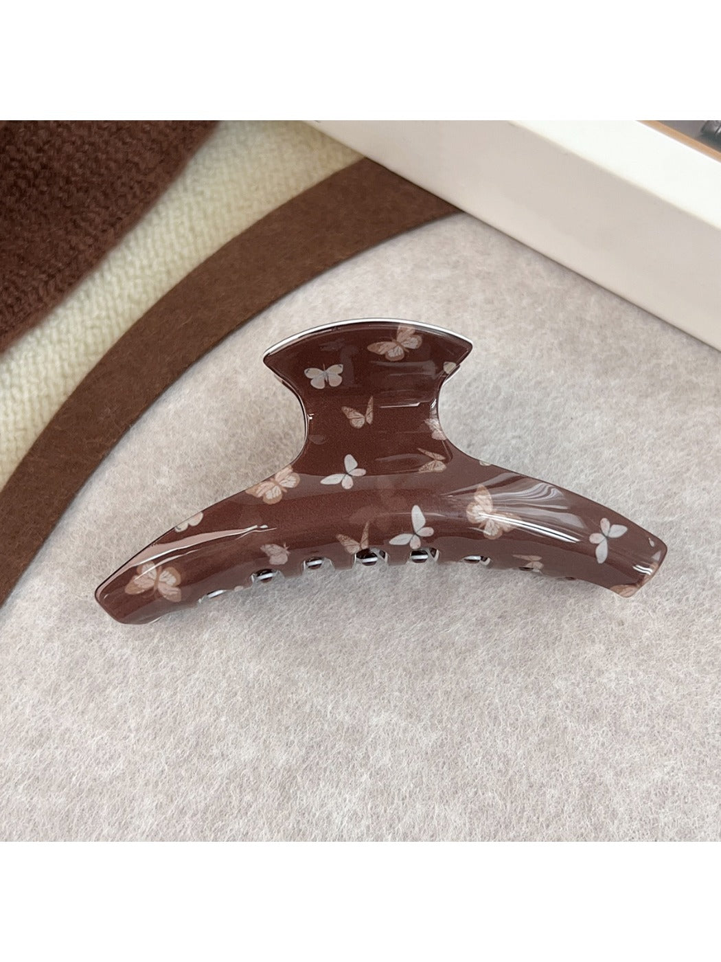 Brown butterfly print claw clip held in hand showing size and shape