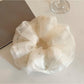 Close-up of beige tulle scrunchie showing delicate sheer fabric texture