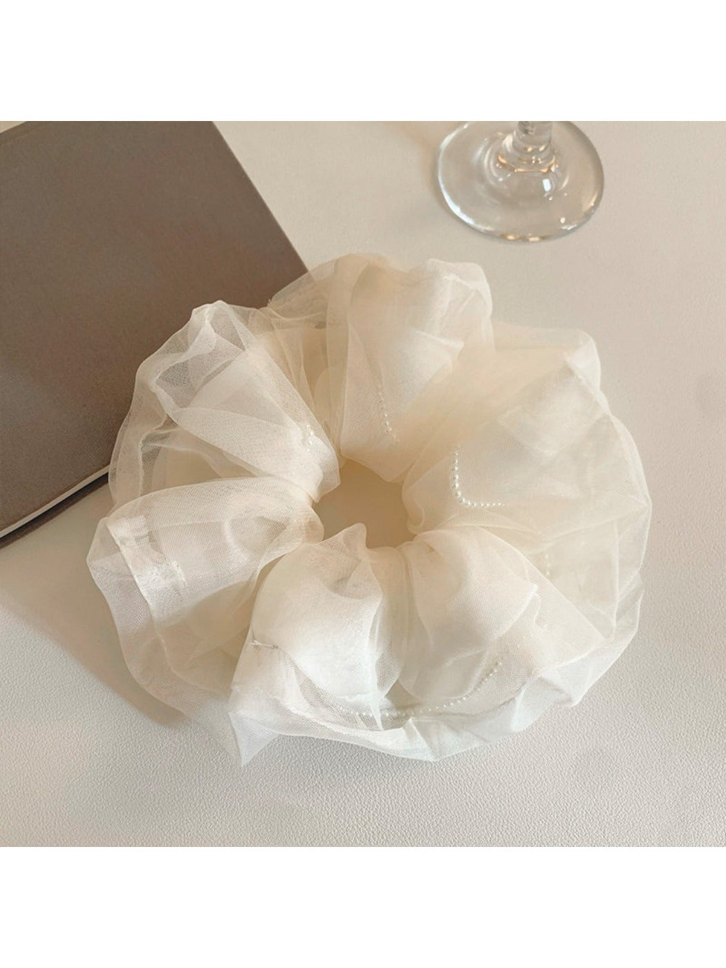Close-up of beige tulle scrunchie showing delicate sheer fabric texture