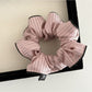 Multiple Gifty striped scrunchies stacked to show variety of colors and stripes