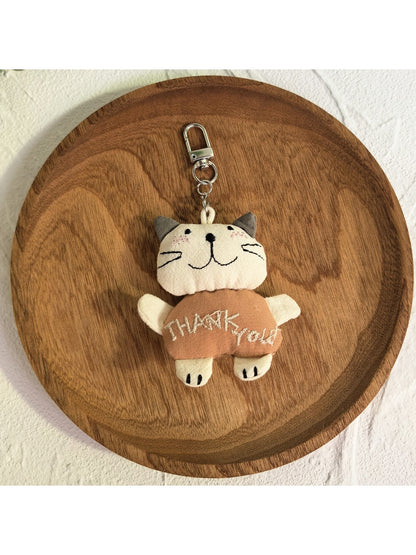 Cartoon cat keychain attached to a set of keys on a wooden surface