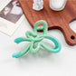 Beau heart shaped bow claw clip with ombre pink to purple gradient on a model's hair
