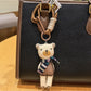 Fabric bear cub keychain hanging from a metal keyring on a wooden surface