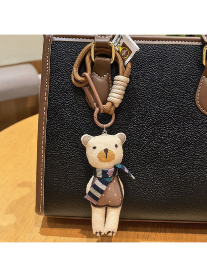 Fabric bear cub keychain hanging from a metal keyring on a wooden surface