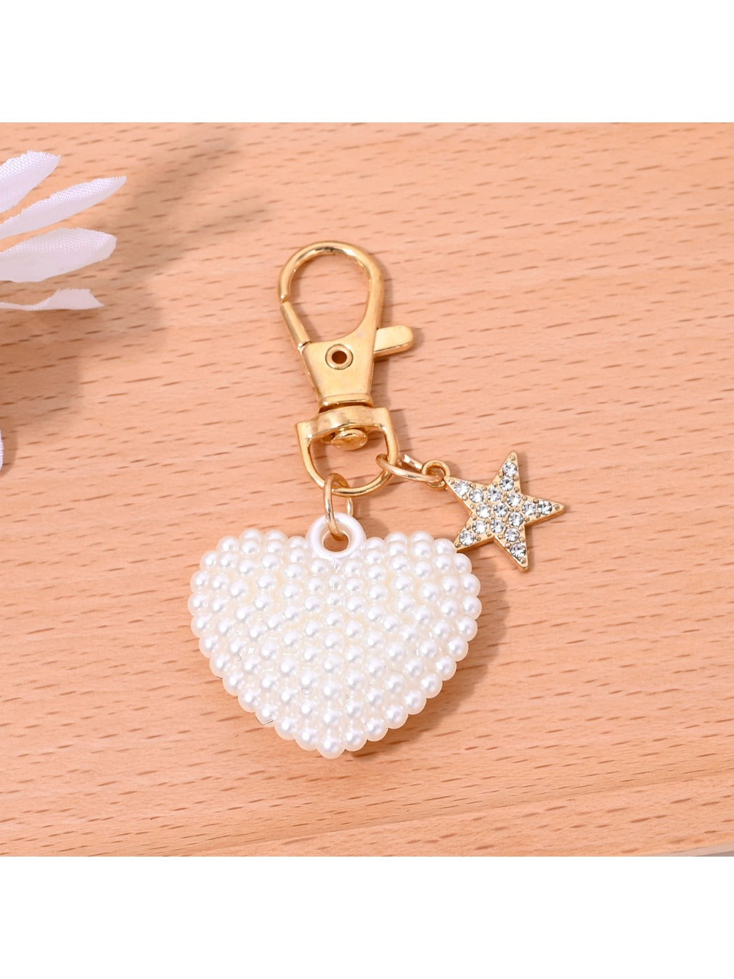 Heart shaped bag charm keychain attached to a set of keys on a white background