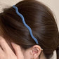 Denim wave headband styled with loose hair on a wooden surface