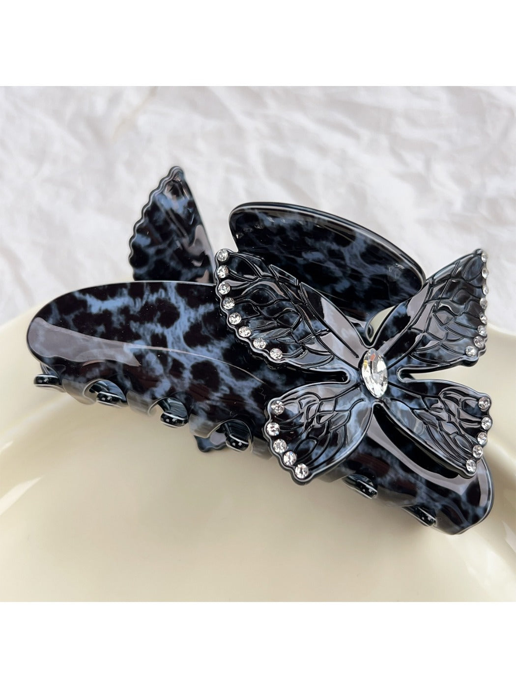 Beau leopard print claw clip held in hand showing size and butterfly design