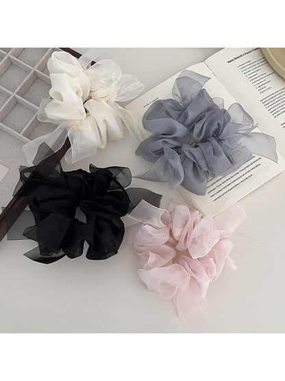 Close-up of Gifty stylish scrunchie with bow accent in soft pink fabric