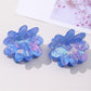 Blue floral hair clip worn in brown hair, styled in loose waves