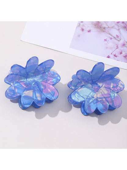 Blue floral hair clip worn in brown hair, styled in loose waves
