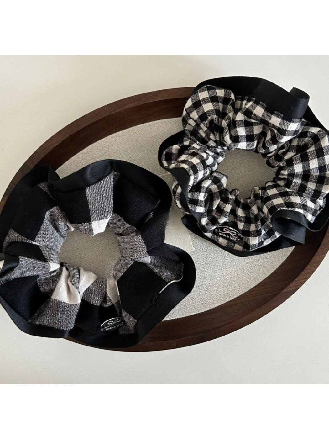 Scrunchie stretched to show elastic inside with black edge and check pattern