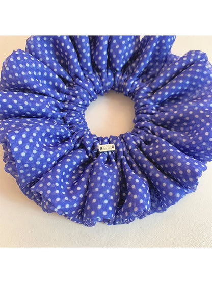 Blue polka dot scrunchie styled on a wrist as an accessory