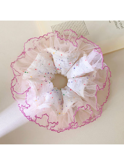 Close-up of ruffled fabric with multicolored polka dots on scrunchie
