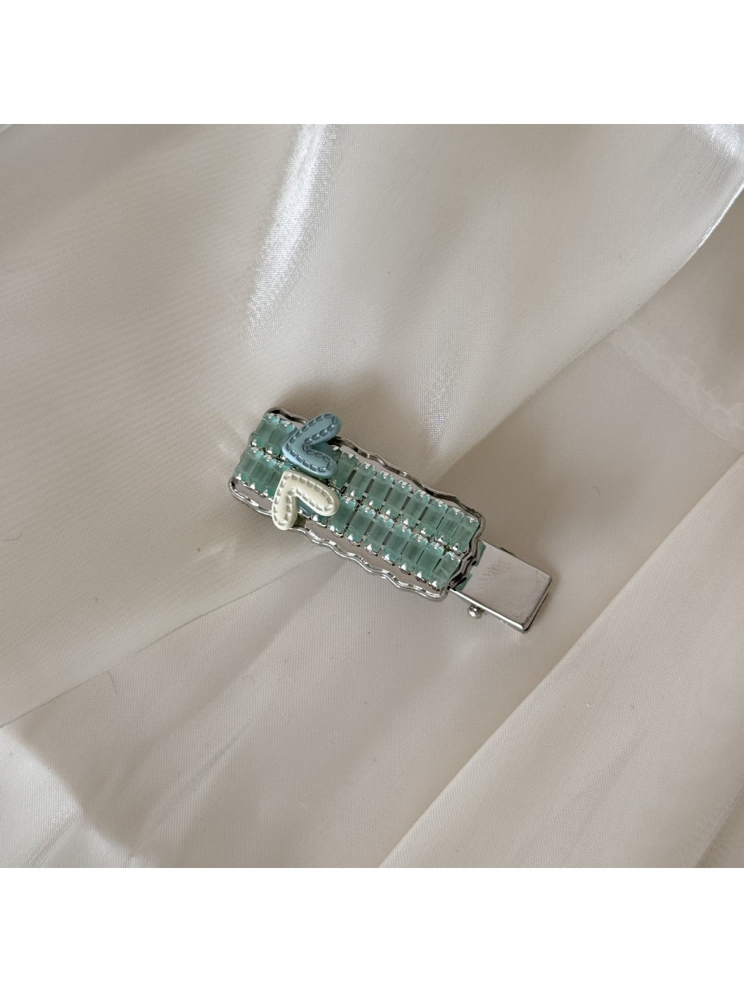 Beau chic flat hair clip resting on a textured fabric surface