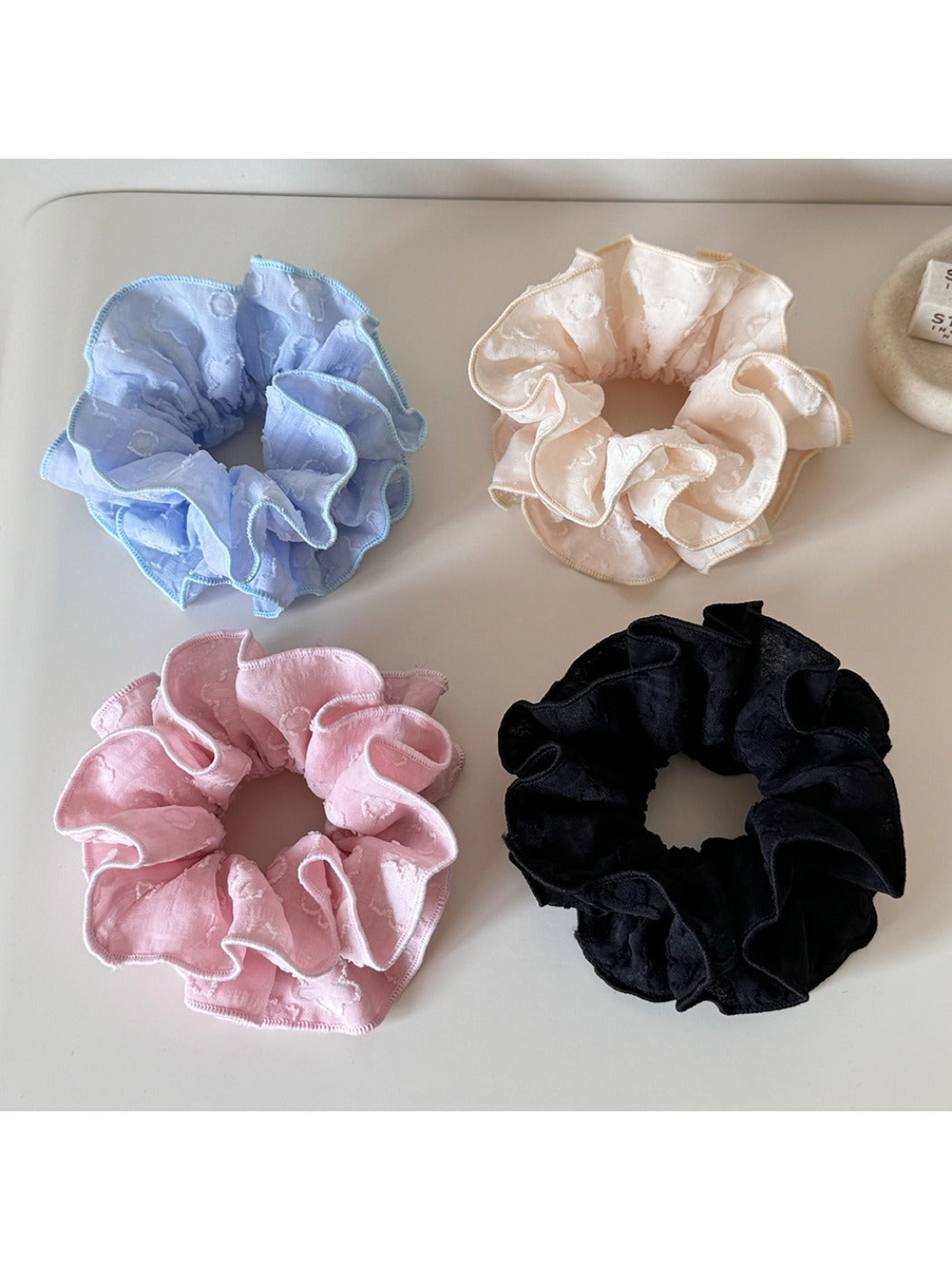 Close-up of Gifty Sweet Style floral print scrunchie with pink and white flowers on fabric