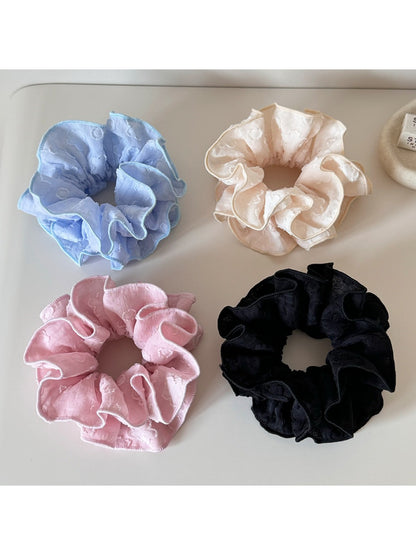Close-up of Gifty Sweet Style floral print scrunchie with pink and white flowers on fabric