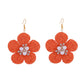 Detailed shot of raffia fibers in flower-shaped earrings showing craftsmanship and texture