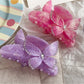 Beau hair claw clip held in hand displaying size and butterfly decoration