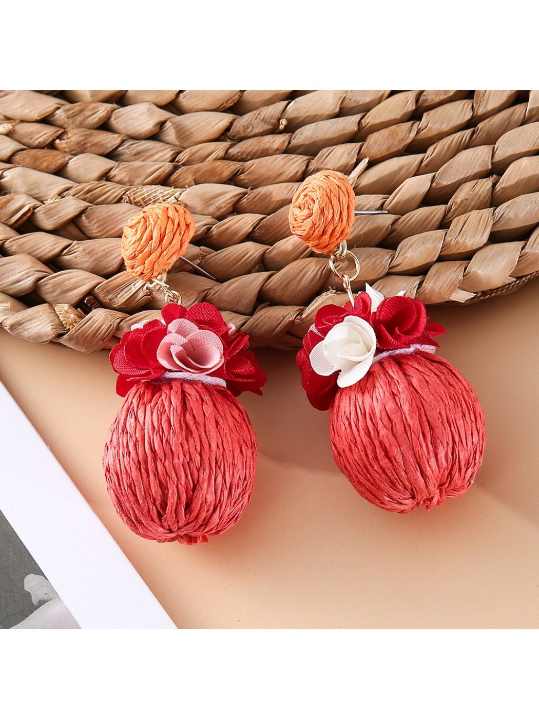 Earedge fabric flower raffia ball earrings displayed on a jewelry stand