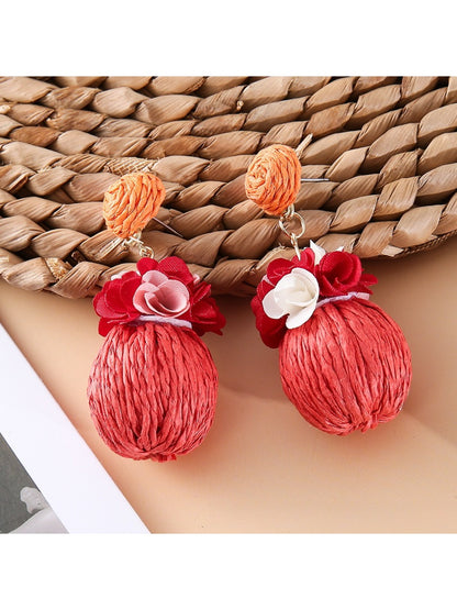 Earedge fabric flower raffia ball earrings displayed on a jewelry stand