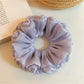 Purple reflective tulle scrunchie styled on a wrist with soft lighting