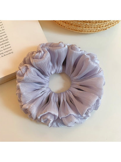 Purple reflective tulle scrunchie styled on a wrist with soft lighting