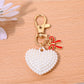 Red heart shaped bag charm keychain with gold clasp shown against a black background