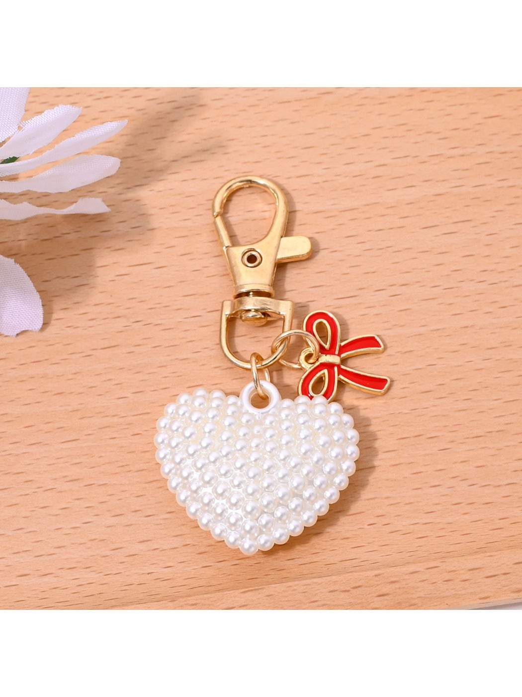 Red heart shaped bag charm keychain with gold clasp shown against a black background