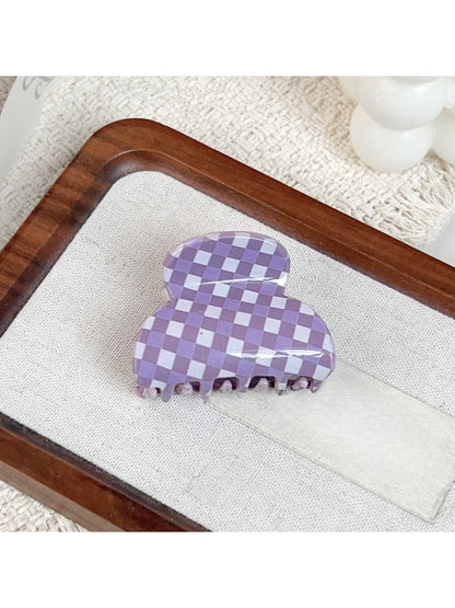 Purple plaid hair claw clip placed on wooden surface