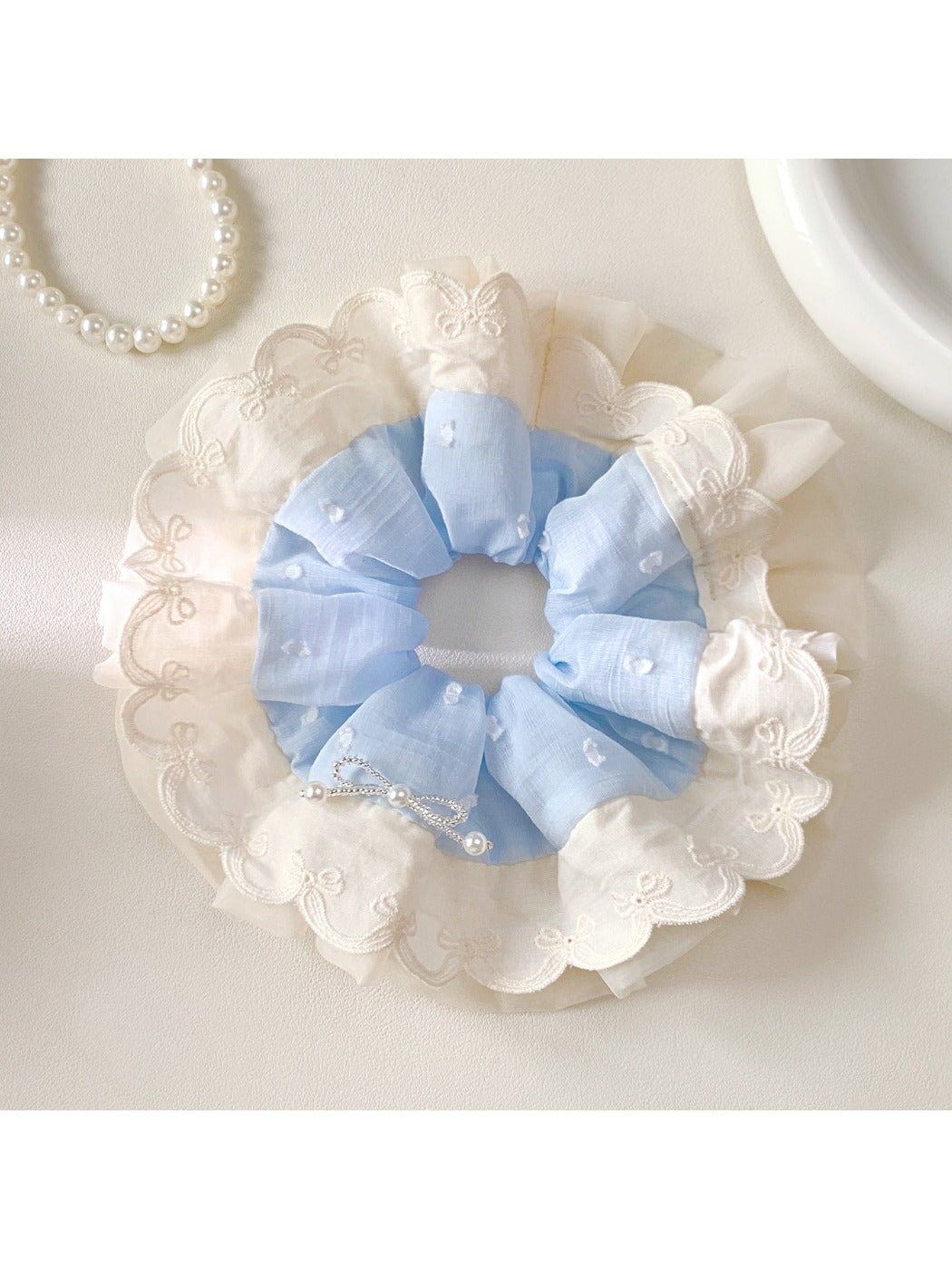 Gifty minimalist scrunchie styled on a wrist with white fabric and black polka dots