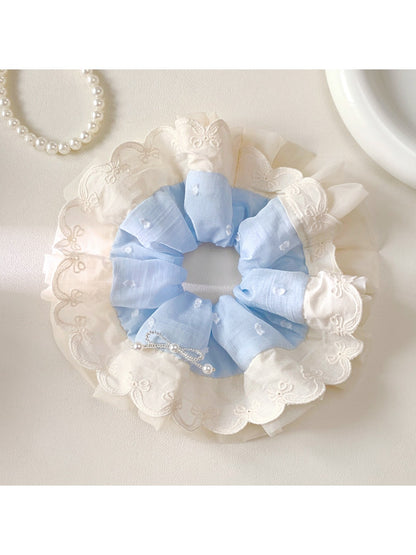 Gifty minimalist scrunchie styled on a wrist with white fabric and black polka dots