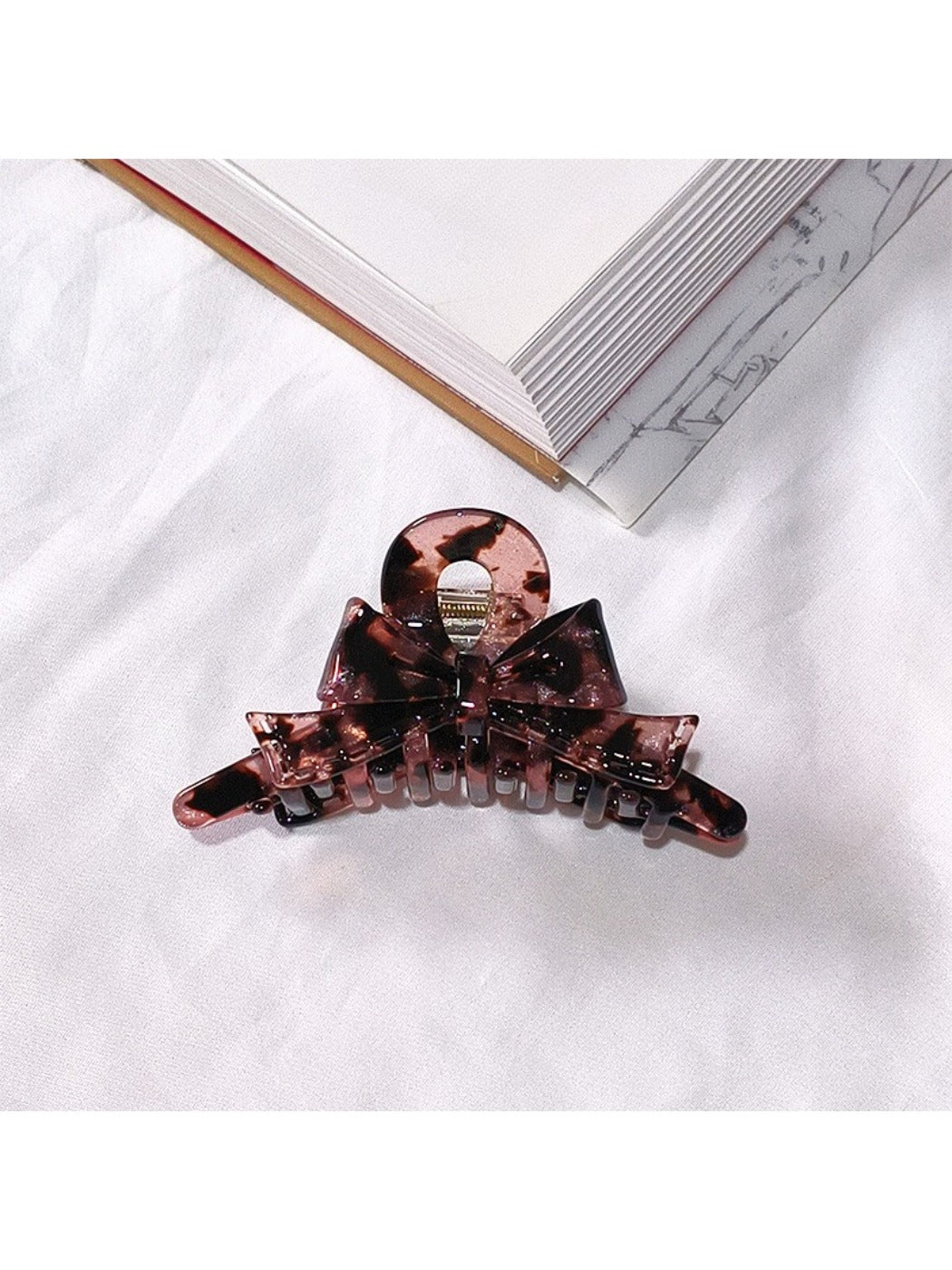 Beau acetate bow shaped claw clip on fabric background for texture contrast