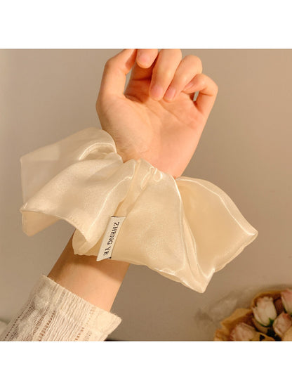 Gifty shiny scrunchie styled on a model's wrist with casual outfit