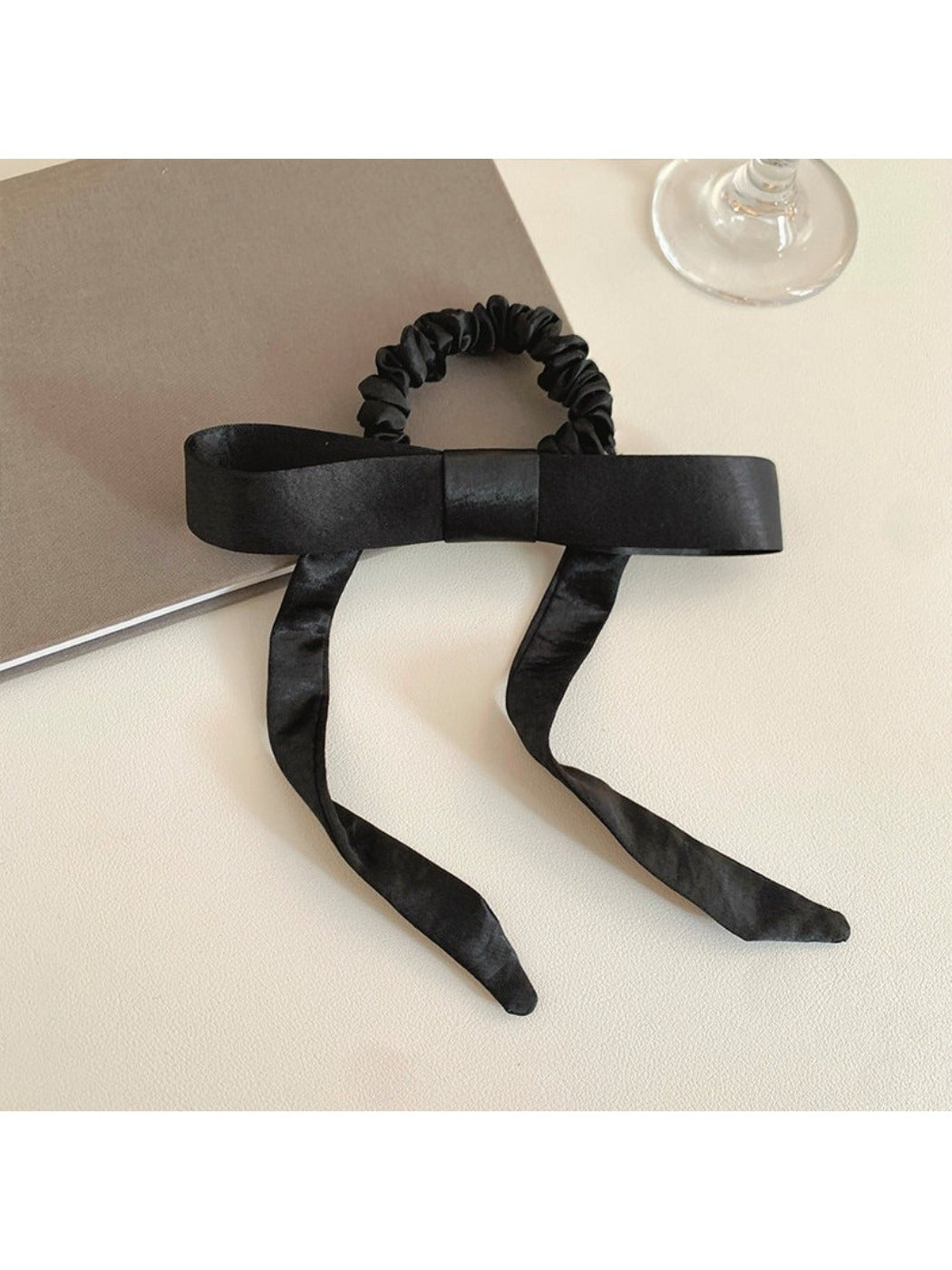 Satin bow hair tie wrapped around a ponytail on a model with brown hair