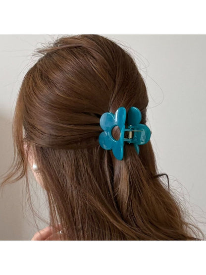 Side view of beige flower shaped claw clip with metal spring visible