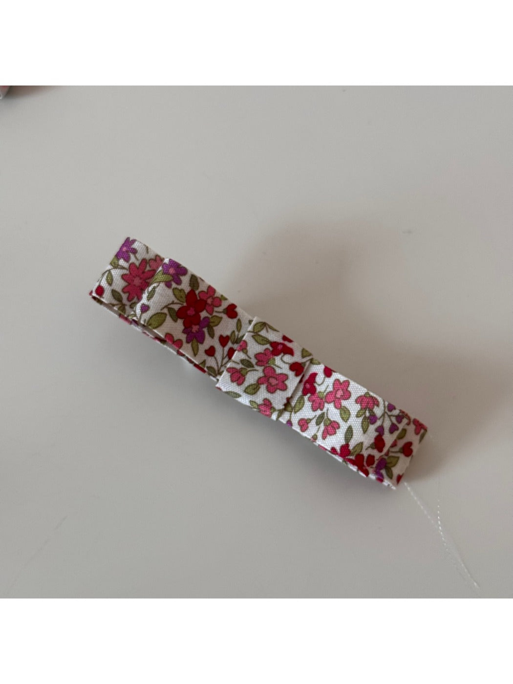Beau pink floral hair clip next to pink flowers for color comparison