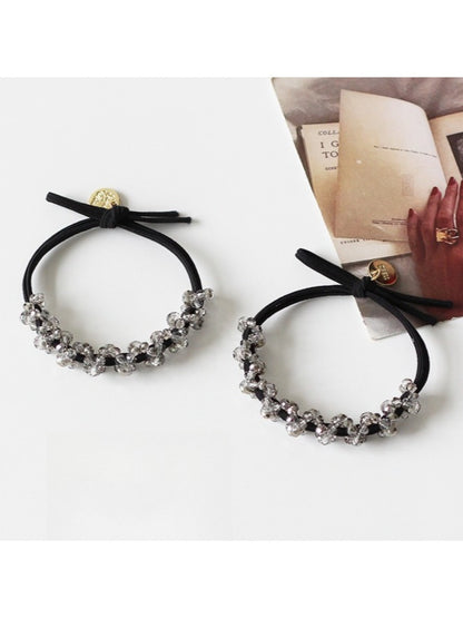 Gifty hair tie stretched to show elasticity and bead details on a white background