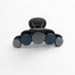 Beau hair clip resting on a wooden table with soft shadows