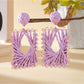 Close-up of raffia material and square shape of Earedge earrings