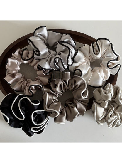 Gifty satin scrunchie worn on a model's wrist as a stylish accessory