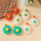 Close-up of Earedge raffia flower shaped drop earrings on white background
