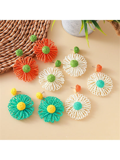 Close-up of Earedge raffia flower shaped drop earrings on white background