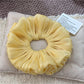 Solid color satin ruched scrunchie styled in a casual hair bun